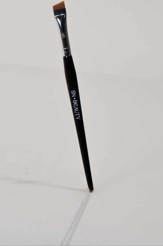 Pinceau biseauté noir SN BEAUTY posé verticalement sur fond clair, manche brillant avec logo blanc.